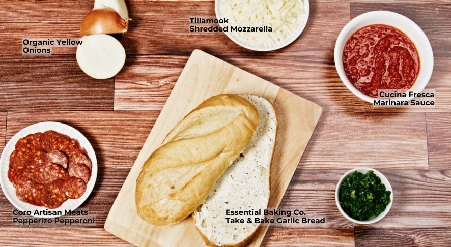 Ingredients spread on wooden board to make pepperoni pizza